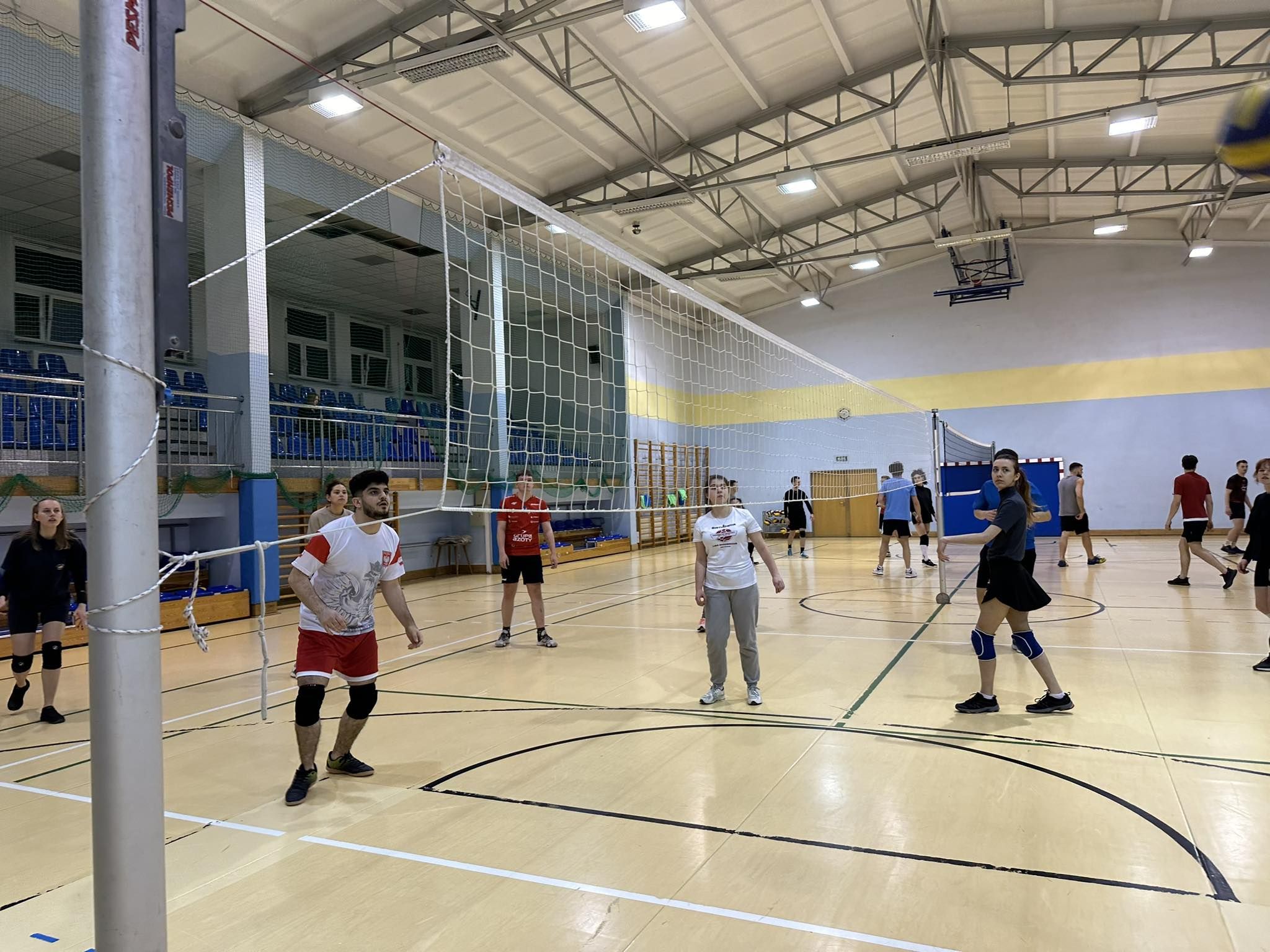 Erasmus+ students participating in sports classes in a gym, playing volleyball.