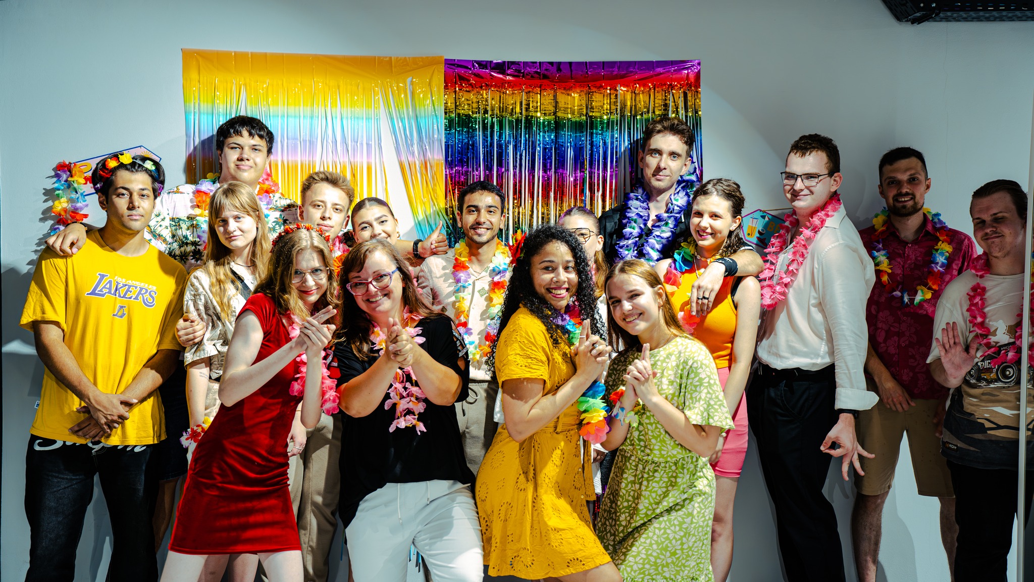 Erasmus+ students in colorful outfits and Hawaiian leis during a themed party.
